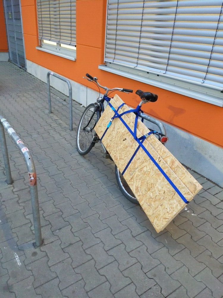 ein Fahrrad, dass hinter OSB Platten verschwindet. Es fehlt nicht viel dazu, dass die auf dem Boden schleifen.