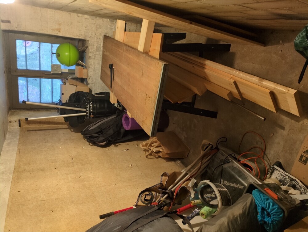 my tiny basement. its got a little working table with the old wooden boards laying on top, and some stuff is piled on the walls around it.